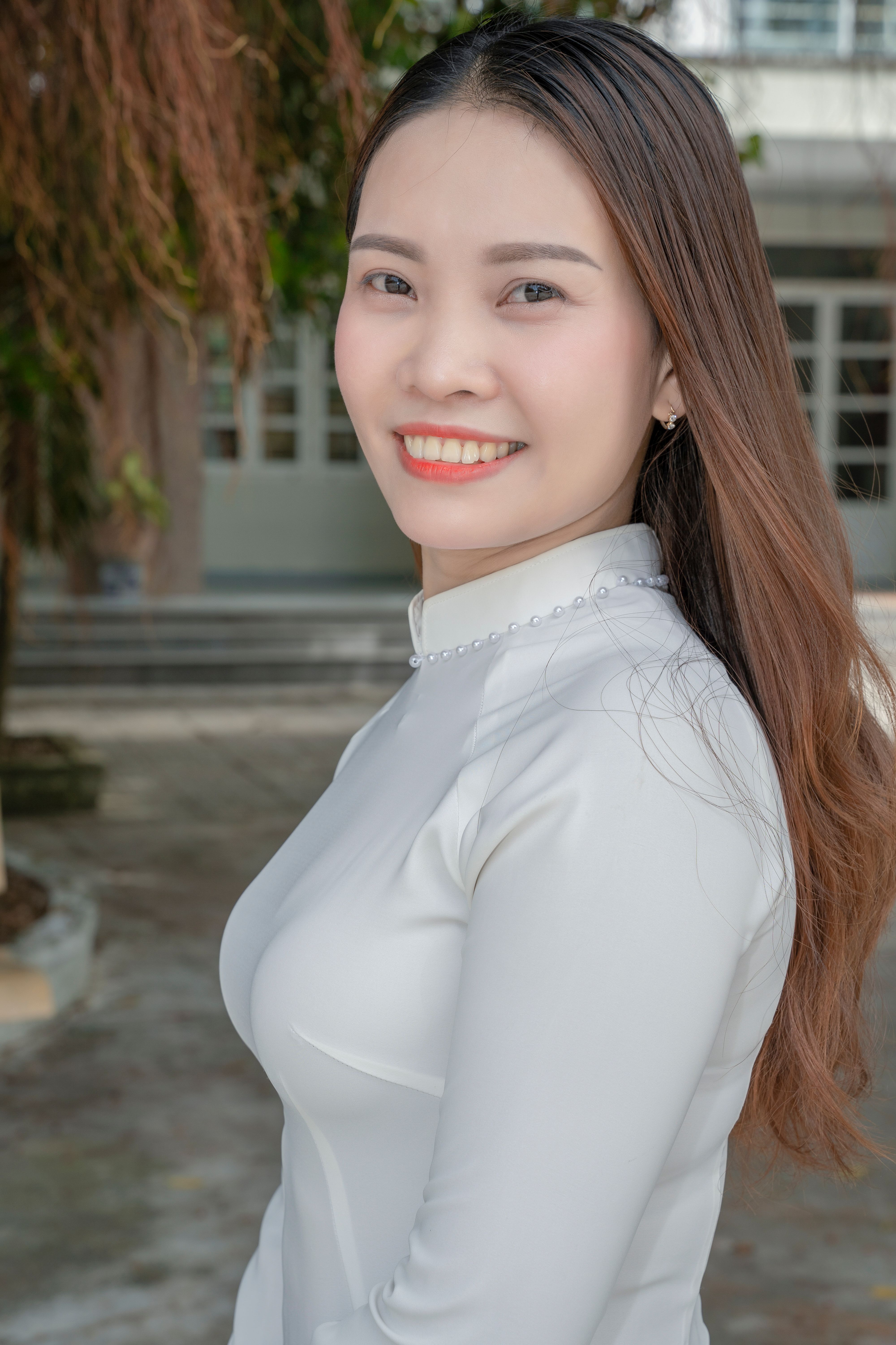 Portrait of a smiling young woman outdoors in a light dress. Bright and natural setting.