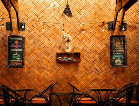 A charming cafe interior featuring a brick wall with vintage coffee signs and cozy seating arrangement.