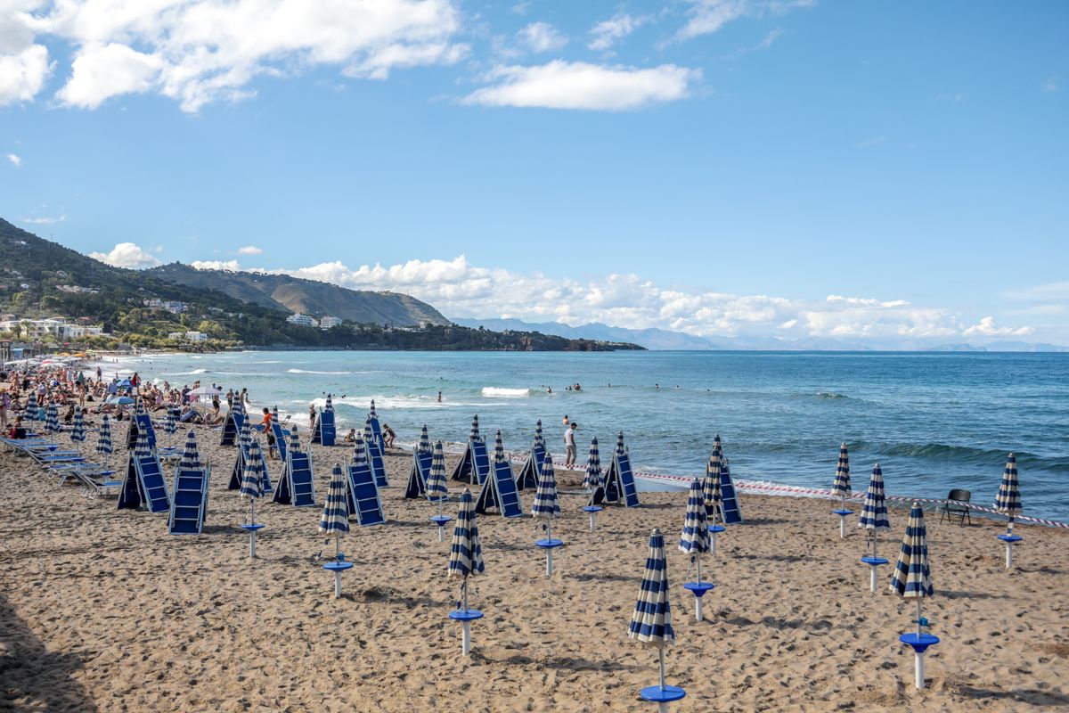 Plajă din Sicilia cu rânduri de umbrele și oameni la soare
