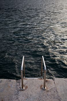 A metal ladder descending from a pier into the Adriatic Sea in Montenegro.