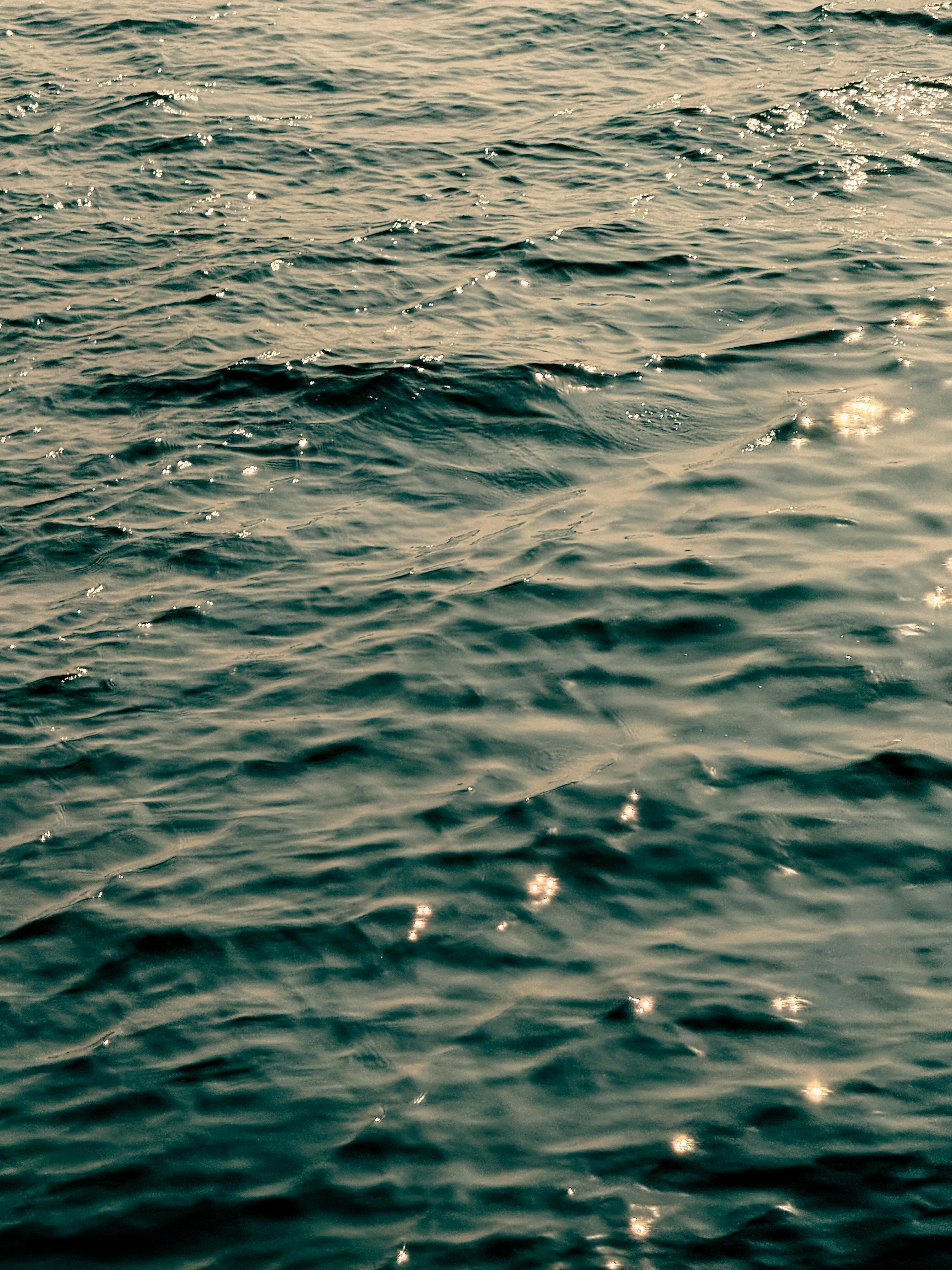 бесплатная Запечатлеть морские волны с искрящимися солнечными отражениями, создающими спокойную и теплую атмосферу. Стоковое фото