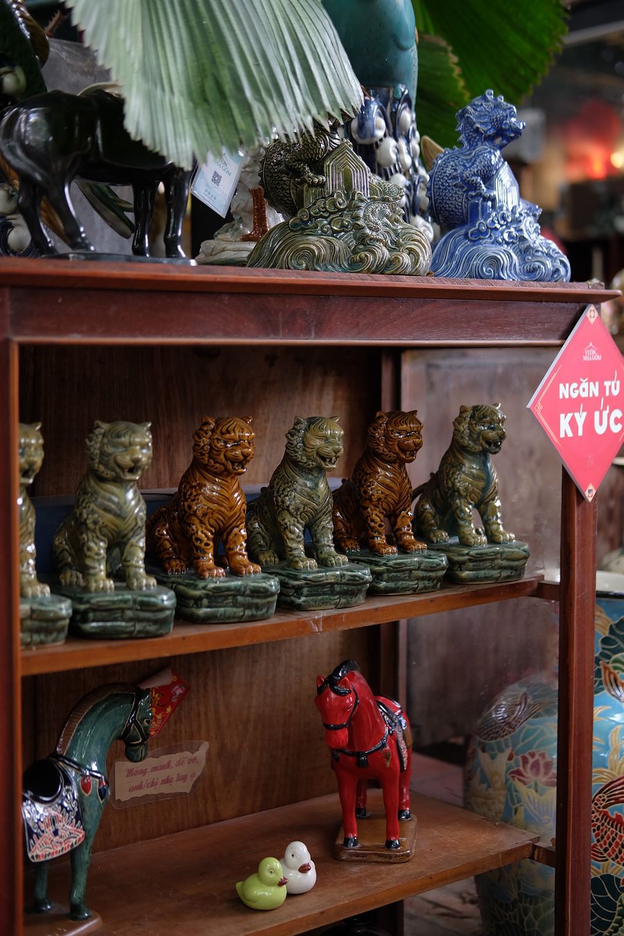 Ceramic figurines crowded on wooden shelves in a vintage shop — photo by bynamnamnam on Pexels