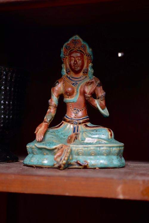Free Intricately designed ceramic deity statue with vivid colors on a wooden shelf indoors. Stock Photo