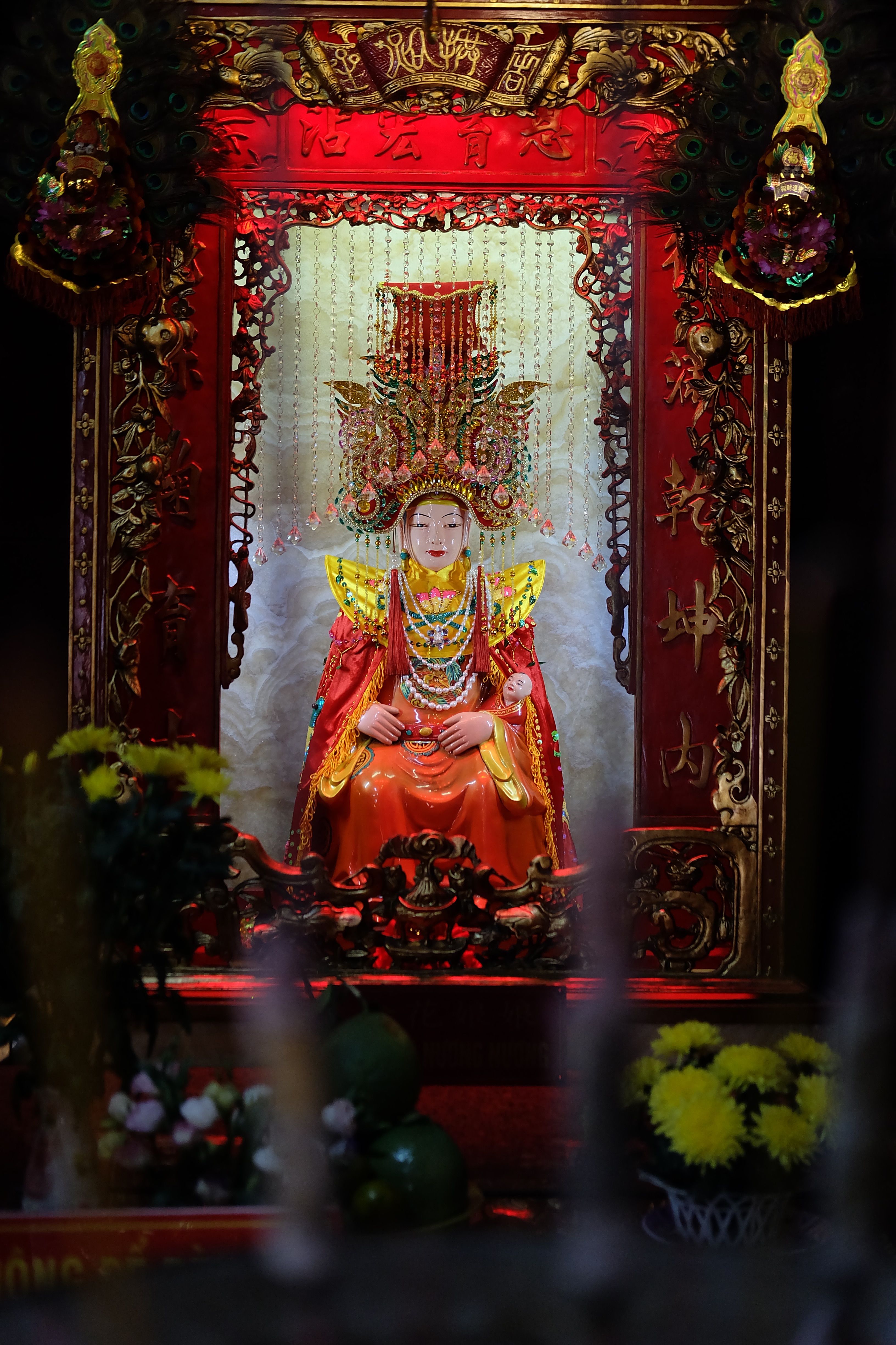 Intricately decorated shrine featuring a colorful deity statue, embodying rich Asian religious artistry.