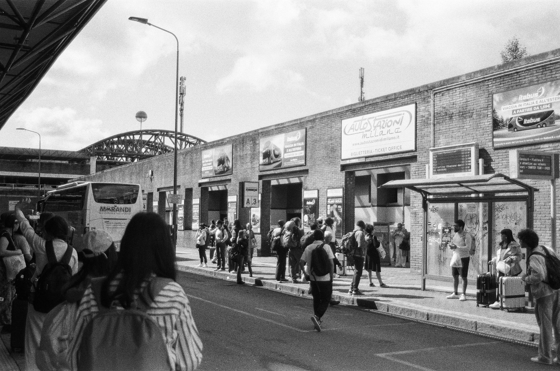 Passeggeri in attesa in una stazione degli autobus a Milano, utile per immaginare l'atmosfera di una partenza su tratte lombarde.
