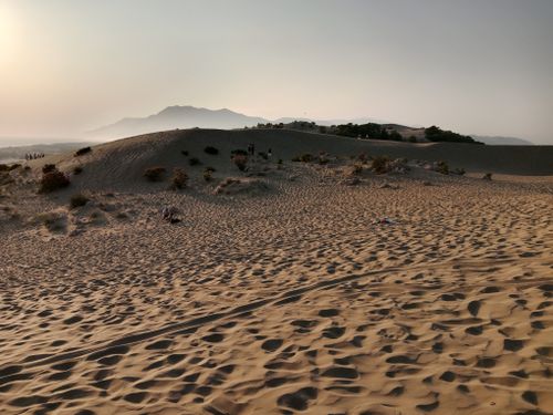 Free A serene desert scene with sand dunes and distant mountains during sunset. Stock Photo