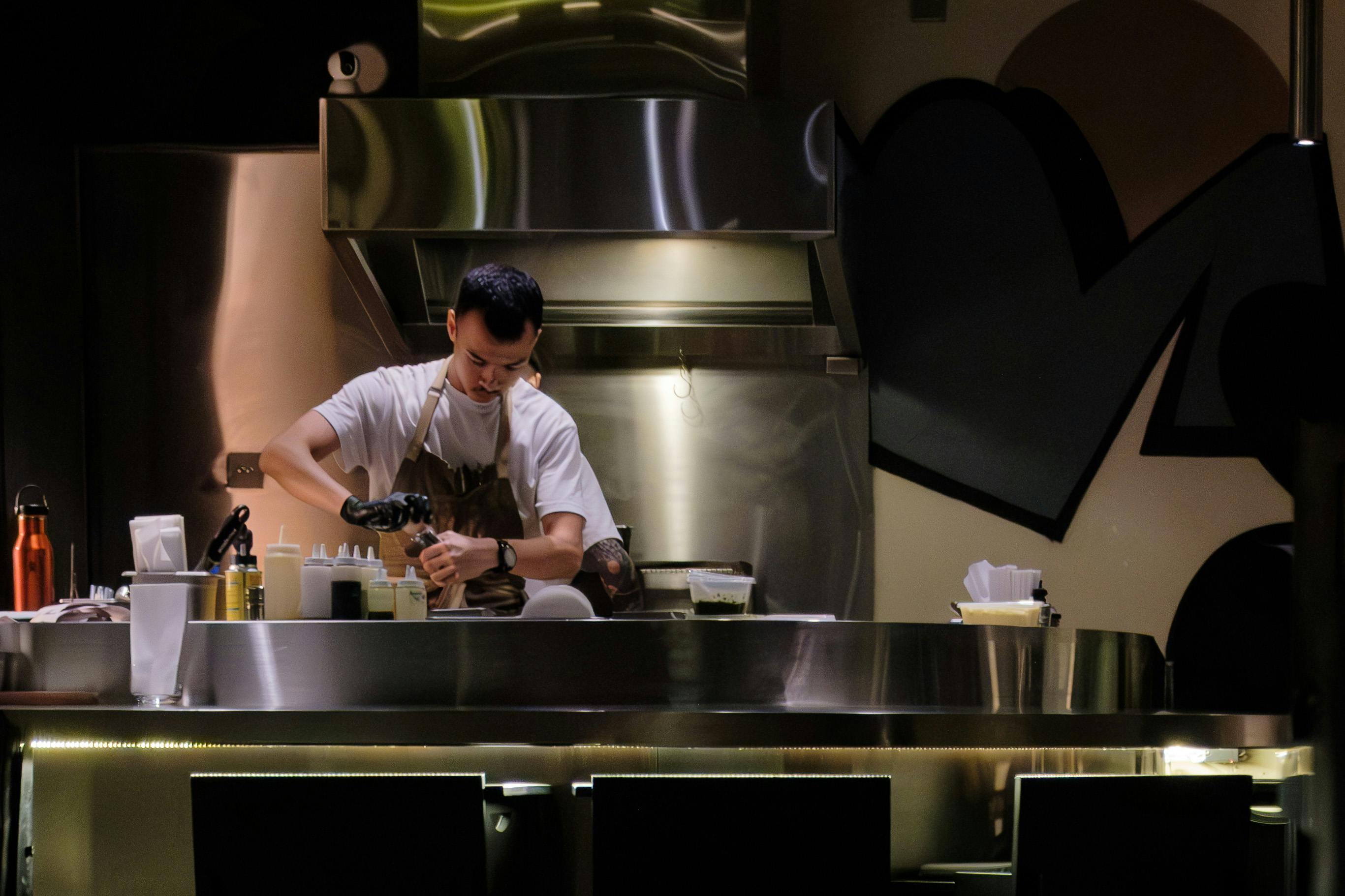 Kitchen Scene With A Man Cooking, Showcasing Culinary Skills And Creativity