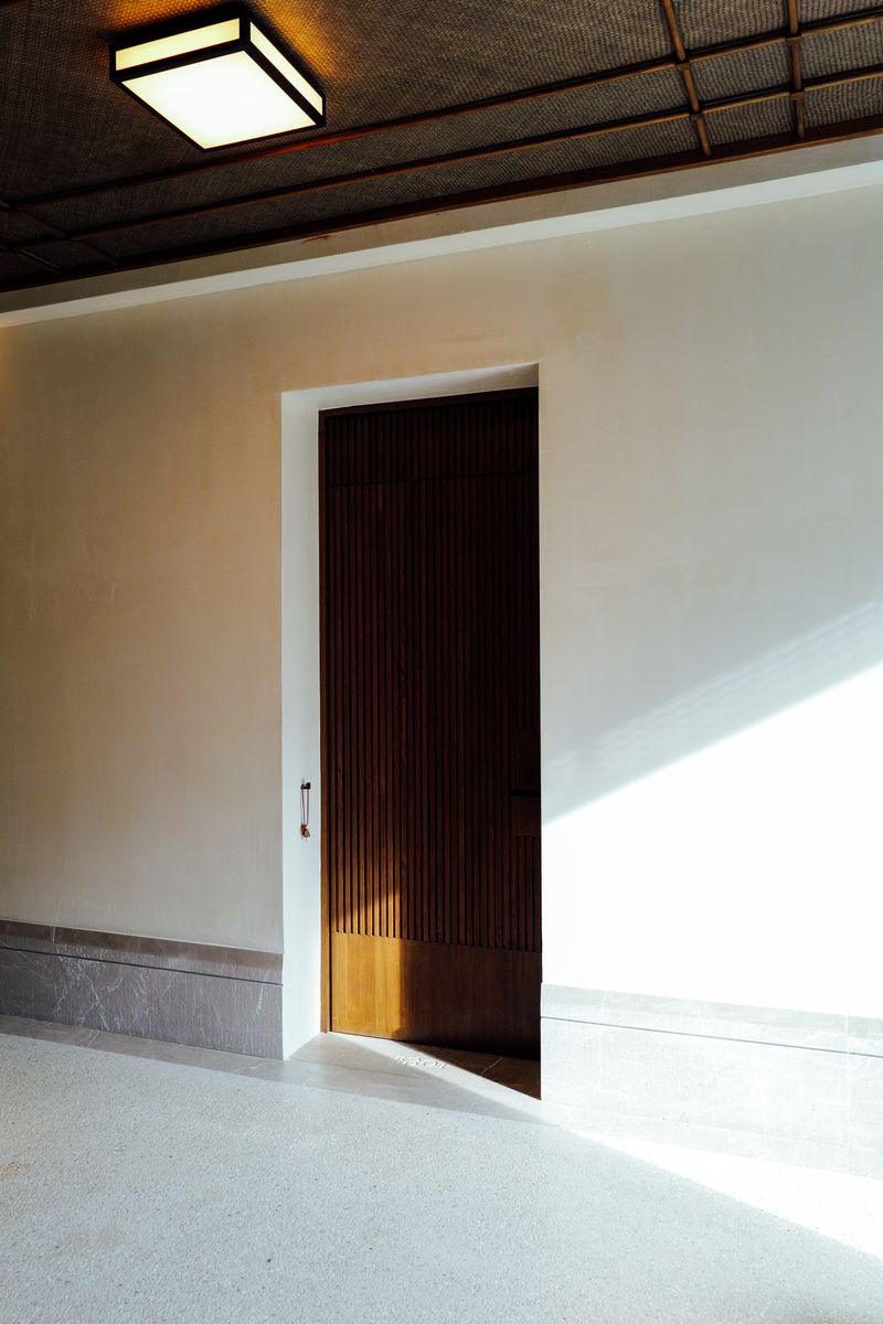 A minimalist indoor setting with a partially open wooden door and elegant lighting.