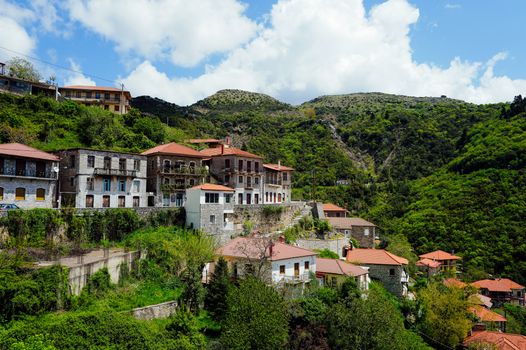 Charming hillside village in Greece surrounded by lush greenery on a sunny day.