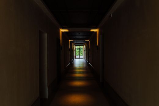Dim corridor leading to a lit doorway — Adrien Olichon on Pexels