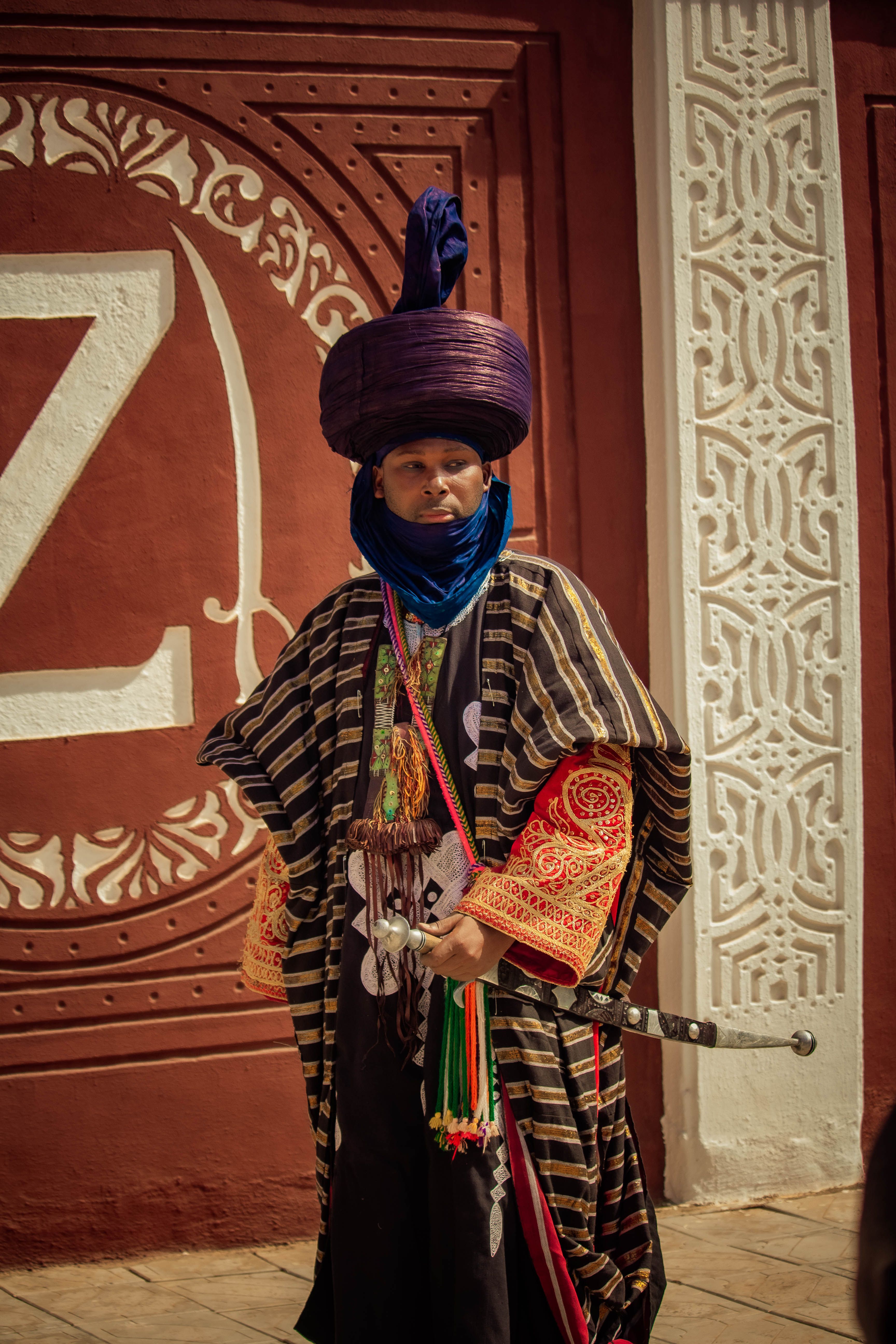 Portrait of a man in traditional African attire, holding a sword. Rich cultural expression.