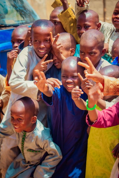 Free A lively group of children smiling and posing outside on a sunny day, exuding happiness and playfulness. Stock Photo