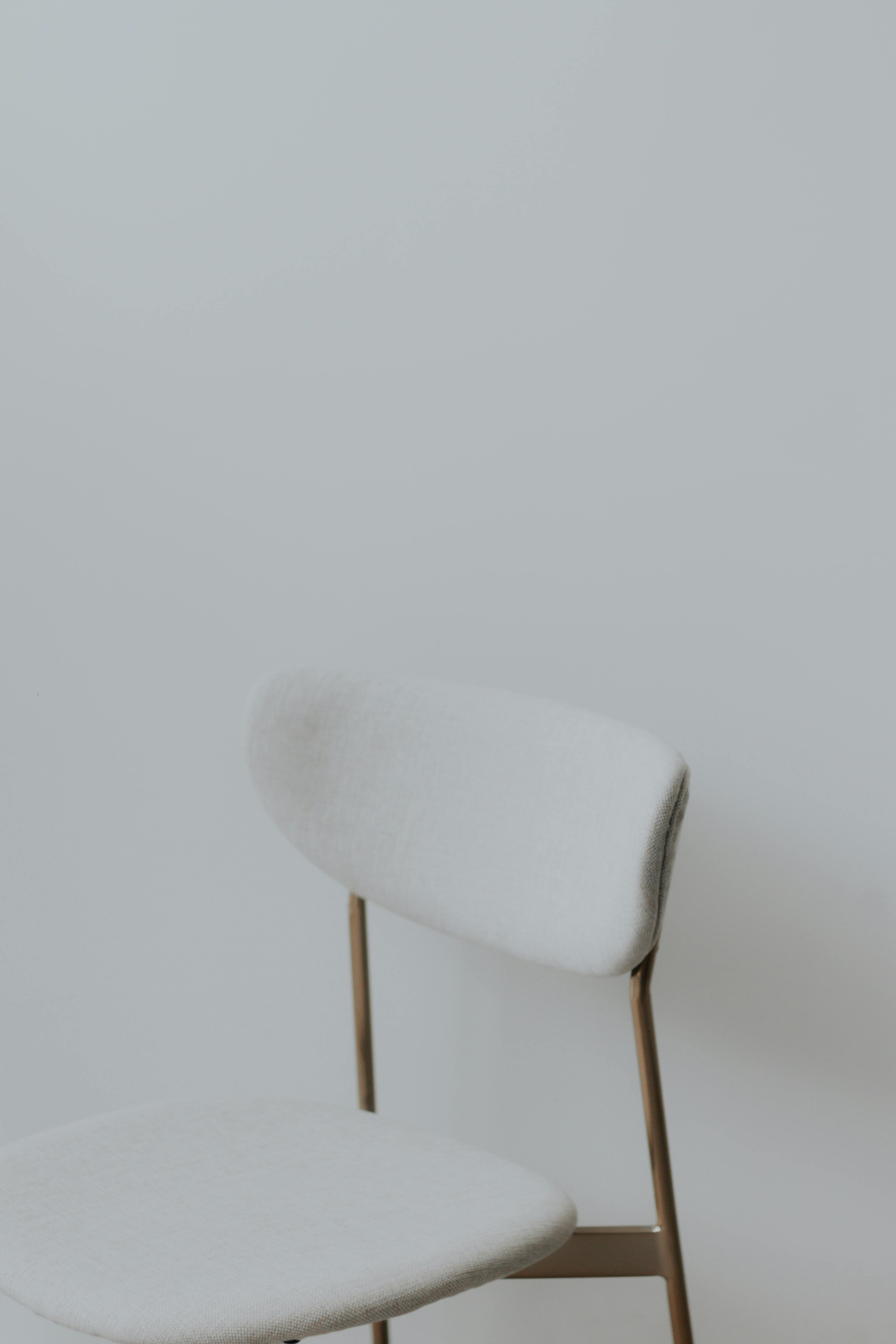 De franc Una cadira minimalista moderna en tela blanca suau sobre un fons neutre clar, perfecta per a temes de disseny d'interiors. Foto d'estoc