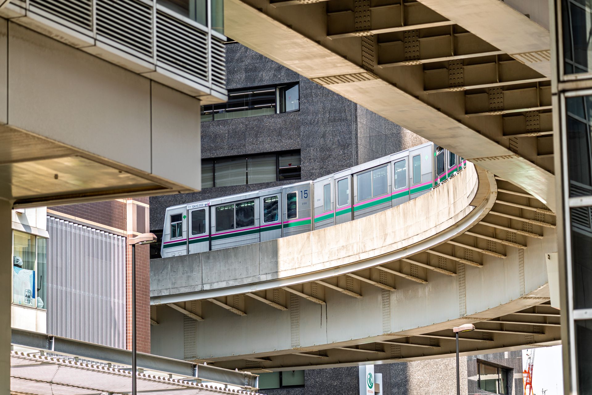 Monorail navigating curved track amid modern architecture in Tokyo, offering urban transport insights.