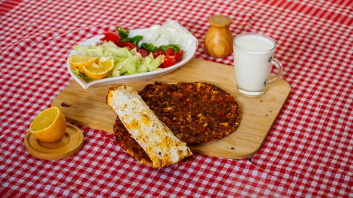 Free A vibrant Turkish meal featuring lahmacun with fresh salad and ayran, served on a wooden board. Stock Photo