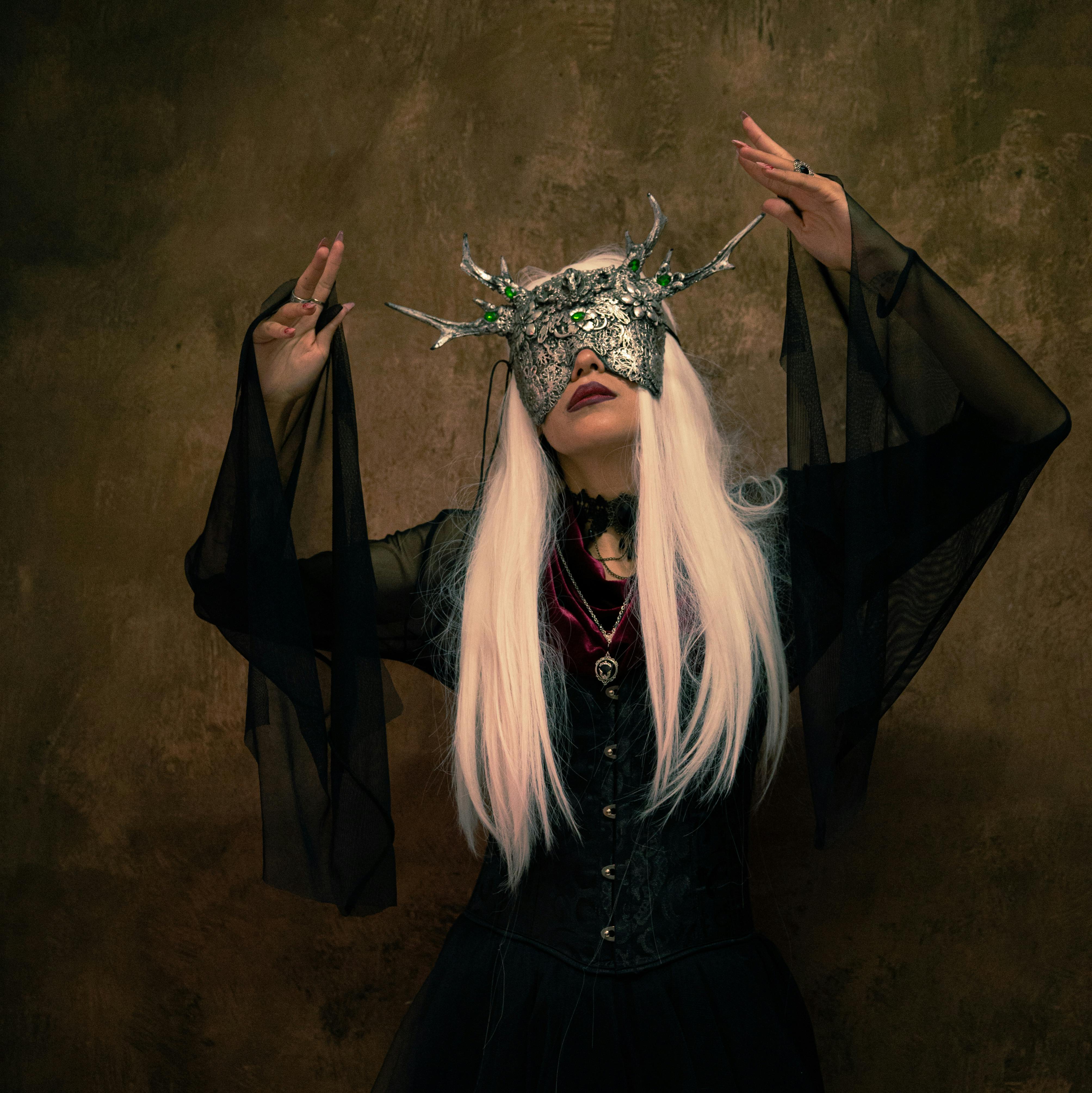 grátis Mulher encantadora em traje gótico usando uma máscara mítica, posando dramaticamente. Foto profissional
