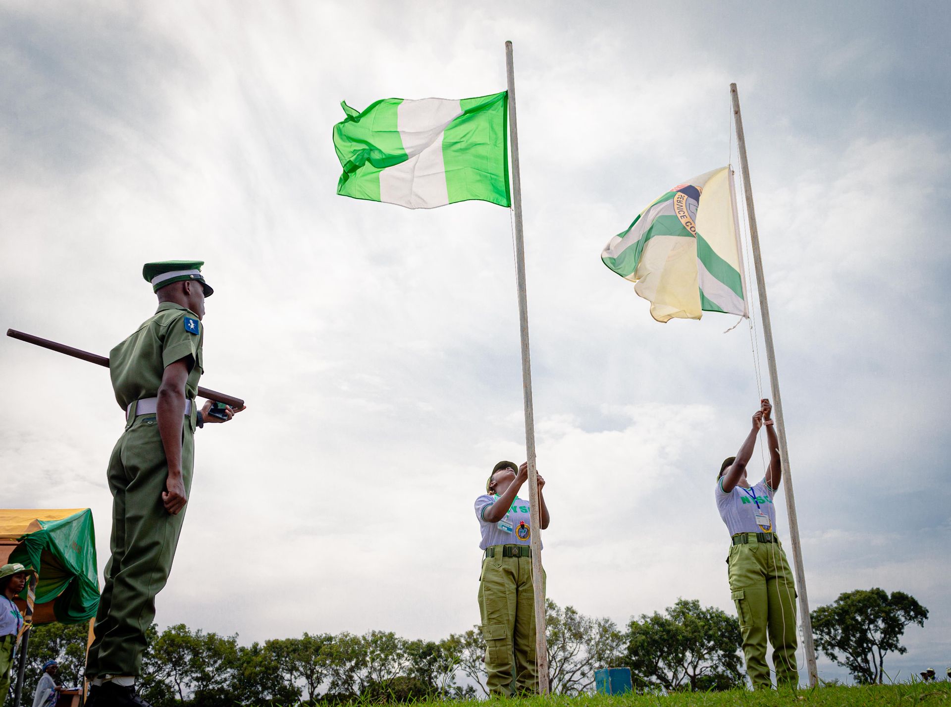 Nigerian youths in uniform raising flags during a national ceremony in Kaduna, Nigeria.