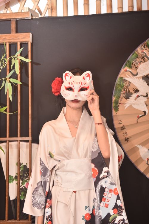 Free Japanese woman in kimono holding a kitsune mask indoors, with traditional decor. Stock Photo