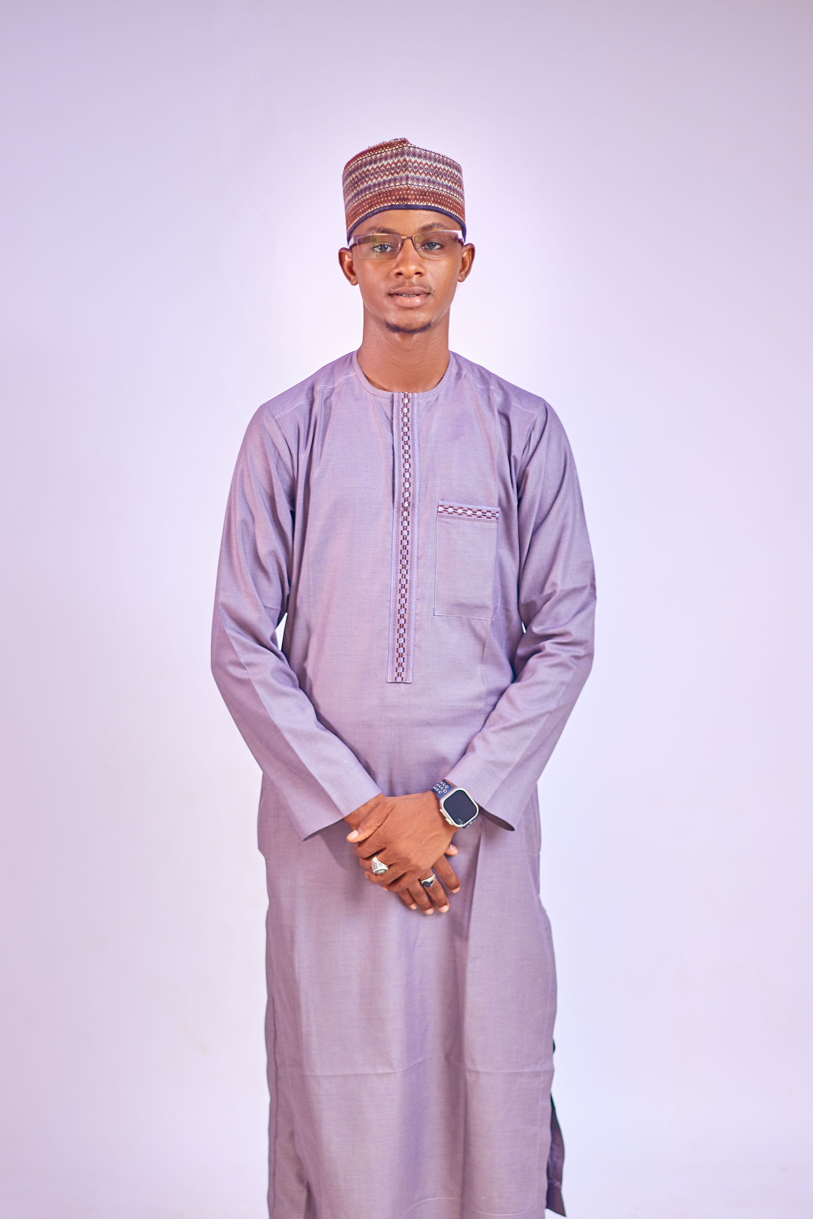 Stylish young man in traditional Nigerian attire wearing a watch, standing with a neutral background.