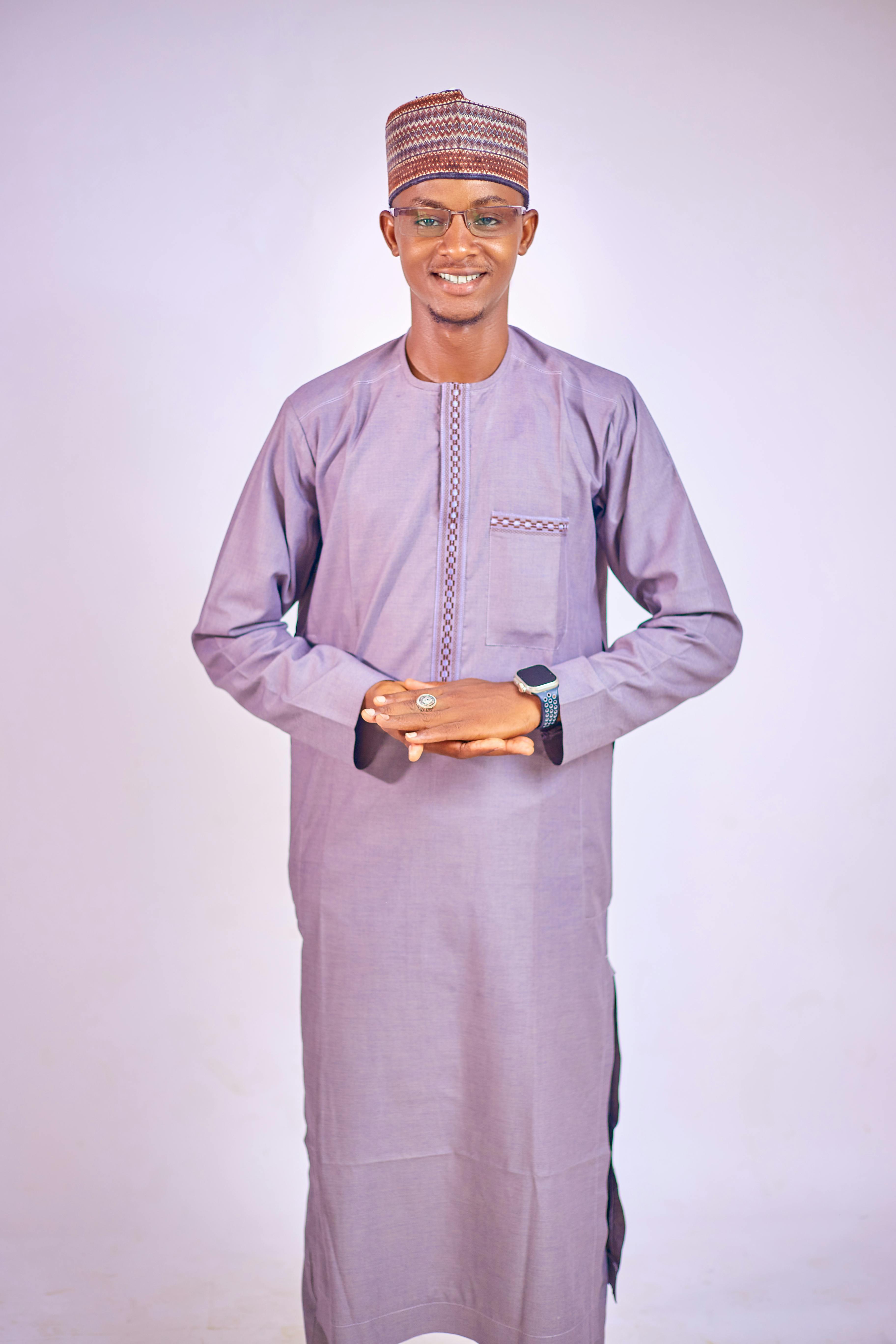 A smiling African man wearing traditional attire poses confidently indoors.