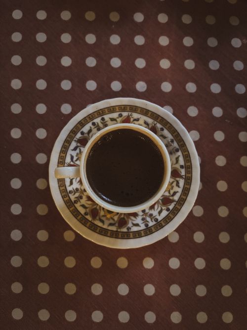 Free Top view of a patterned coffee cup on a polka dot tablecloth, warm and cozy mood. Stock Photo
