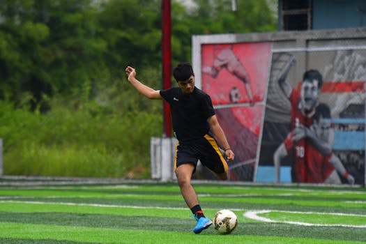 Focused young man playing soccer on a lush green field in Medan, Indonesia.