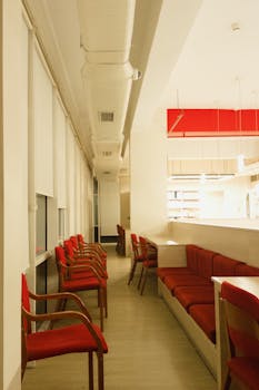 A modern office lounge featuring sleek red seating and bright lighting, perfect for collaborative work or relaxation.