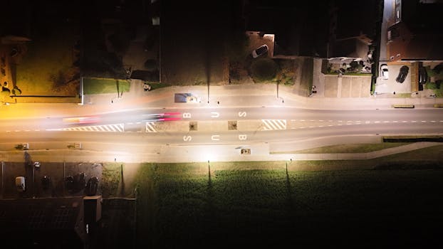 A stunning aerial image captures a Belgian road at night, showcasing motion blur from passing cars.