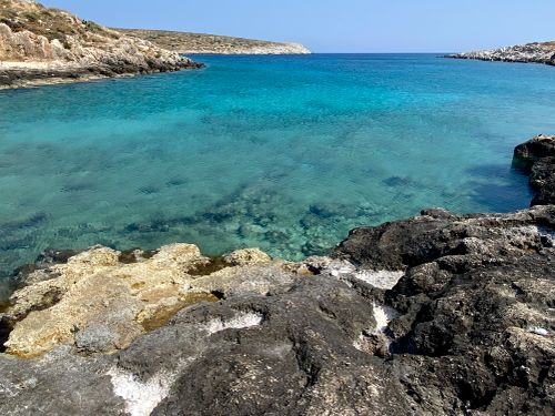 Free Stunning coastal view of Laconia, showcasing the clear blue waters and rocky shoreline under a bright summer sky. Stock Photo