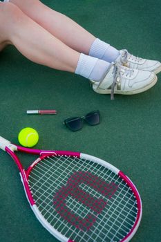 Stylish tennis setup with shoes, racket, ball, and accessories on court.