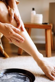 Woman applying natural skincare lotion in a cozy setting, highlighting gentle skin nourishment.