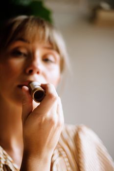 A woman using eco-friendly lip balm in natural lighting, promoting sustainable beauty.