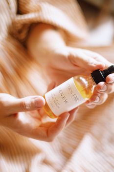 Close-up of hands holding a natural skincare oil bottle, ideal for holistic beauty themes.