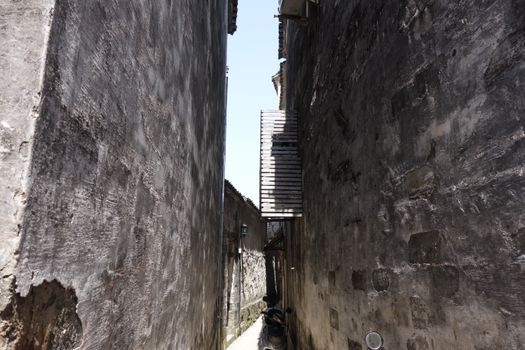 A narrow alleyway with textured walls and dramatic lighting, showcasing urban architecture.