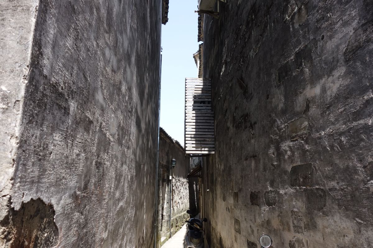 Narrow textured alleyway with dramatic light, typical of Xiamen’s old lanes and Gulangyu Island streets