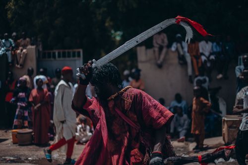 Free Vibrant festival scene with a performer in traditional attire wielding a machete. Stock Photo