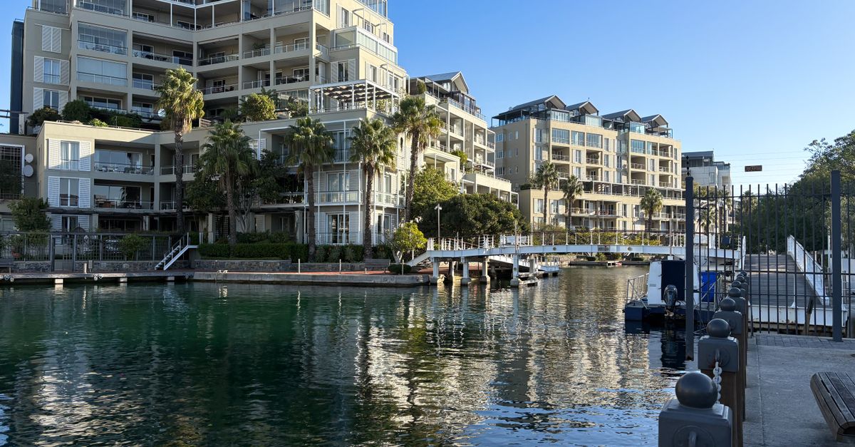 Scenic view of modern apartments at Cape Town waterfront with marina reflection.