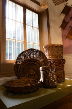 Woven cane baskets displayed in a sunlit indoor museum setting, showcasing traditional craftsmanship.