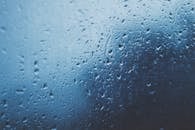 蓝色玻璃窗上水滴的细节特写