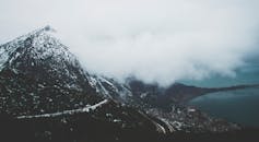 在平静的大海上，一座白雪皑皑的山脉融入雾气的壮丽景色