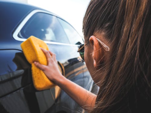 Woman Wiping the Car with Yellow Sponge