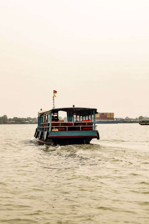 Free A wooden passenger boat sails on a peaceful river under a cloudy sky. Stock Photo