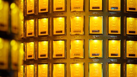 Luminous display of gold bars in a secure vault setting, glowing with golden light.