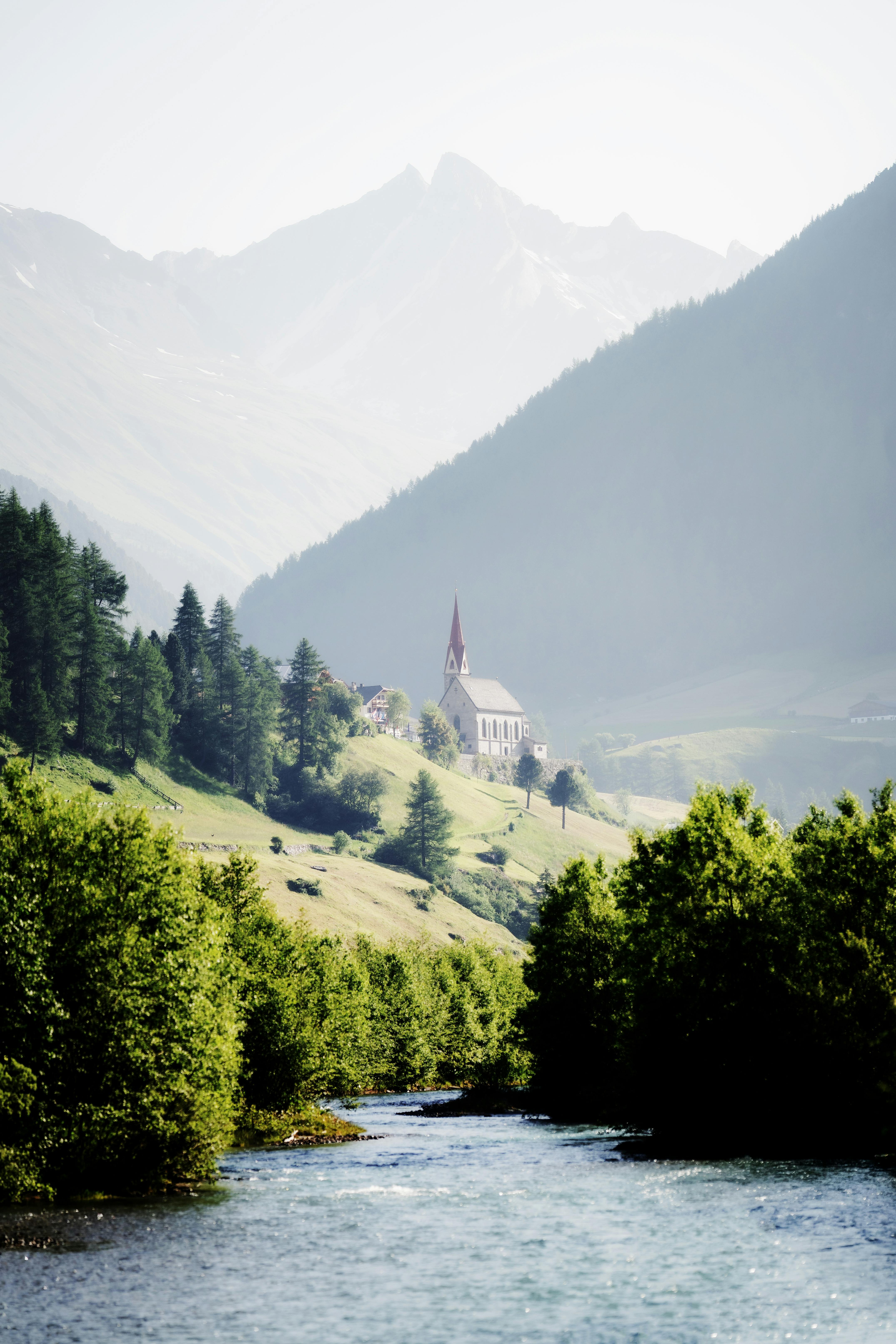 A picturesque Alpine church nestled among lush hills and majestic mountains.