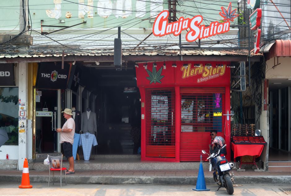 Front view of a Ganja Station store in Pattaya, showcasing cannabis-themed signage and street vendors.