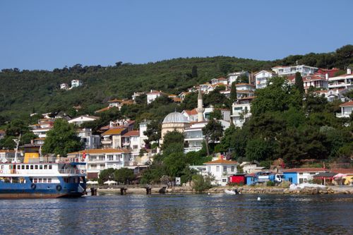 Free Charming coastal town with colorful houses and ferry on a sunny day, showcasing hillside architecture. Stock Photo