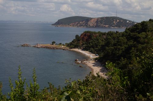 Free A breathtaking view of the coast at Prinkipo Island, showcasing lush greenery and tranquil waters under a partly cloudy sky. Stock Photo
