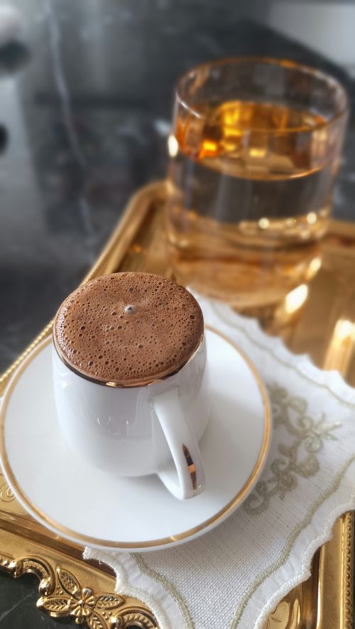 Free Luxurious coffee with frothy top served on a golden tray, perfect for indulgence. Stock Photo