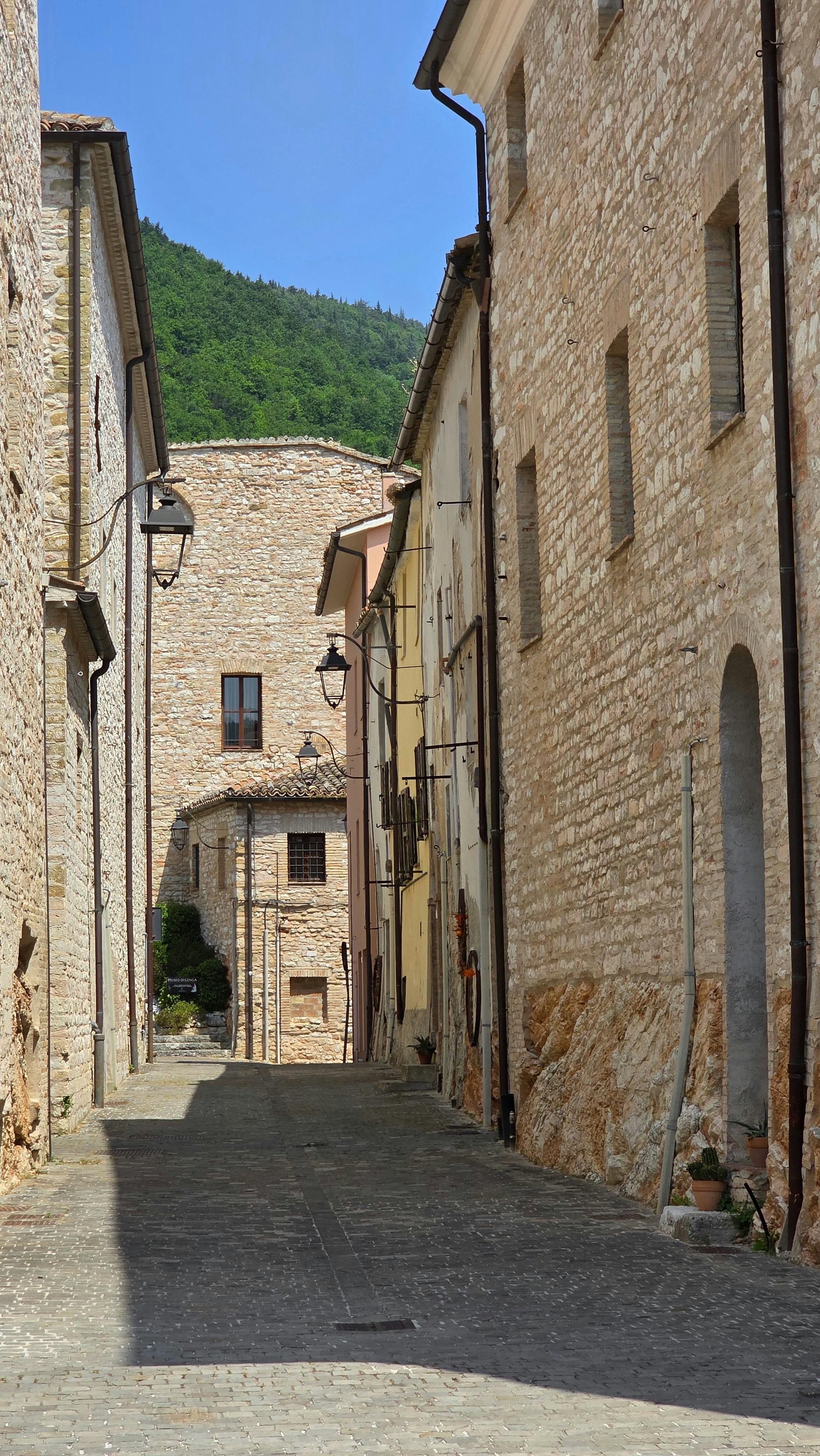 Explore a quaint medieval alleyway with rustic stone buildings under a clear blue sky.