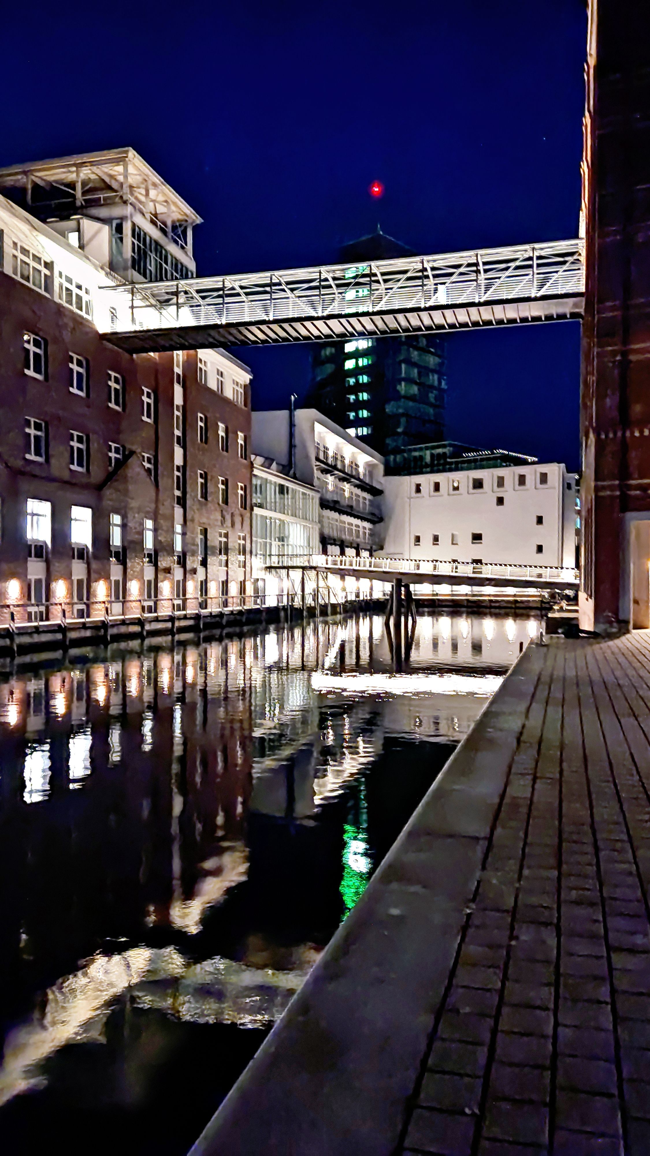 Illuminated modern architecture along the canal in Hamburg's Hafencity at night.